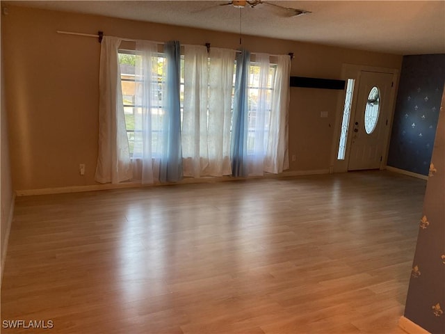 entryway with baseboards, light wood-style floors, and a ceiling fan