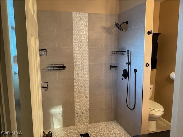 bathroom featuring tiled shower and toilet