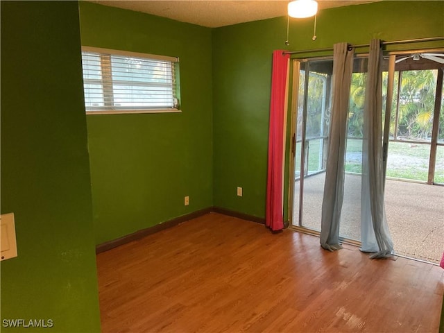 spare room featuring a wealth of natural light, baseboards, and wood finished floors