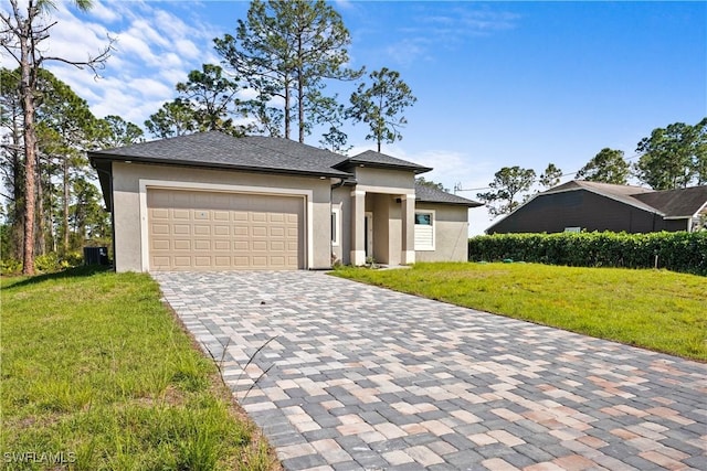 prairie-style house featuring a front lawn, decorative driveway, a garage, and stucco siding