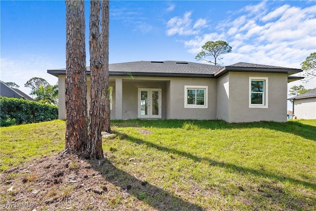 rear view of house with stucco siding, french doors, a shingled roof, and a yard