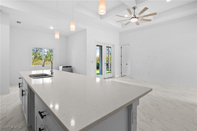 kitchen with a wealth of natural light, marble finish floor, coffered ceiling, and a sink