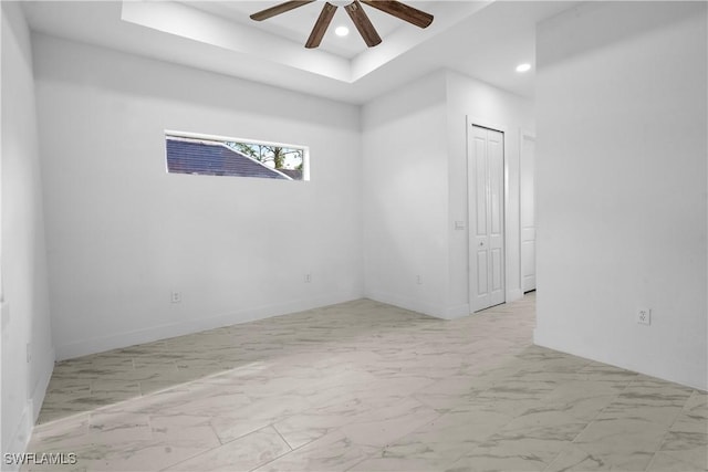 empty room featuring recessed lighting, marble finish floor, a raised ceiling, and a ceiling fan