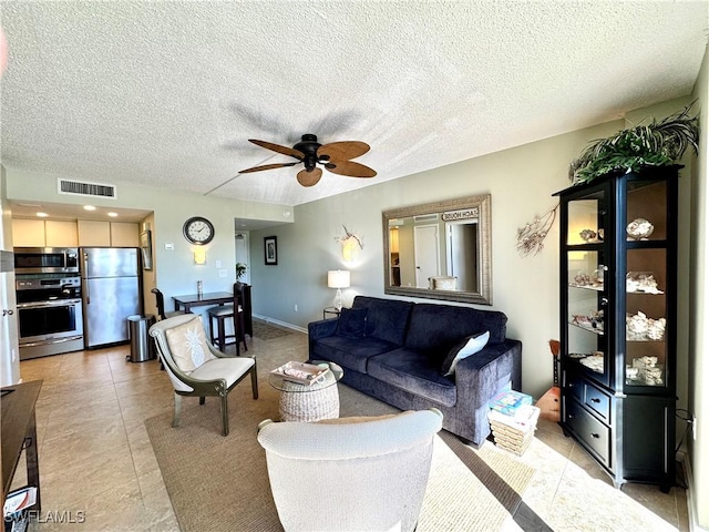 living room with light tile patterned floors, visible vents, a textured ceiling, and ceiling fan