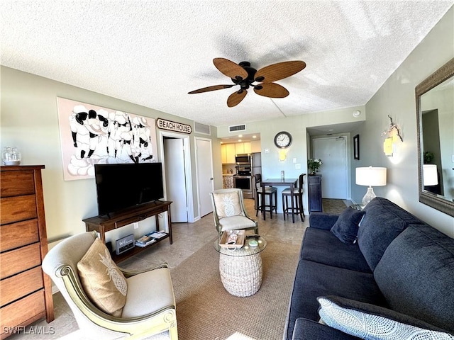 living area with ceiling fan, visible vents, and a textured ceiling