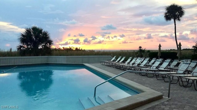 pool at dusk featuring an outdoor pool and a patio