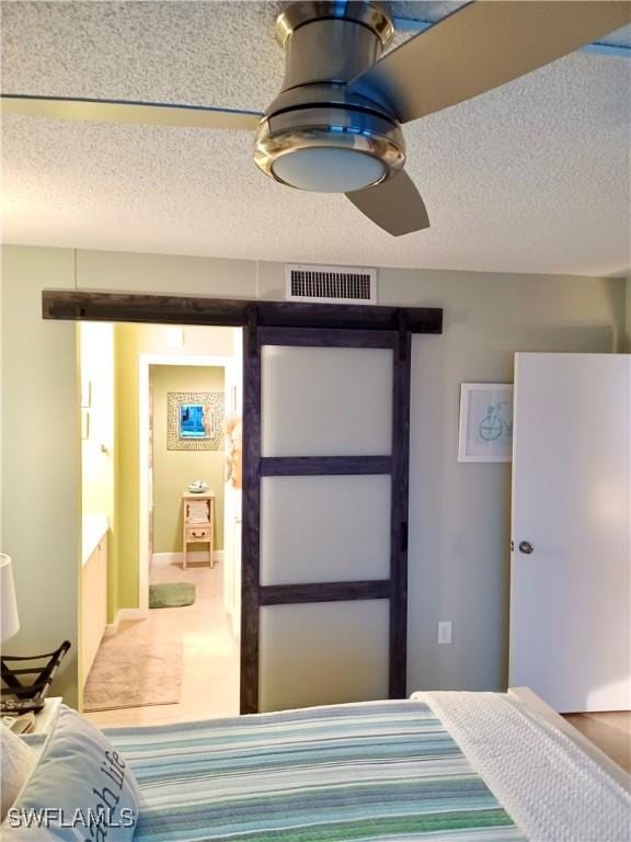 bedroom with a barn door, visible vents, and a textured ceiling