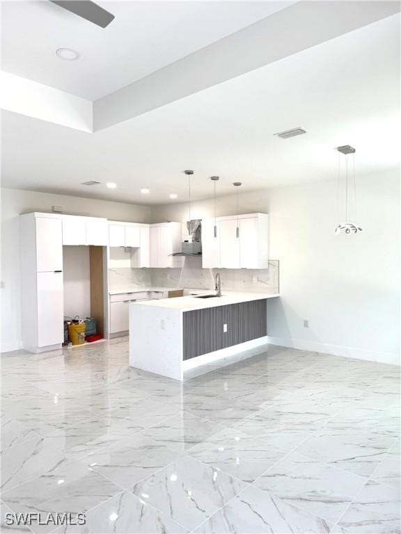 kitchen with visible vents, marble finish floor, range hood, white cabinetry, and a peninsula