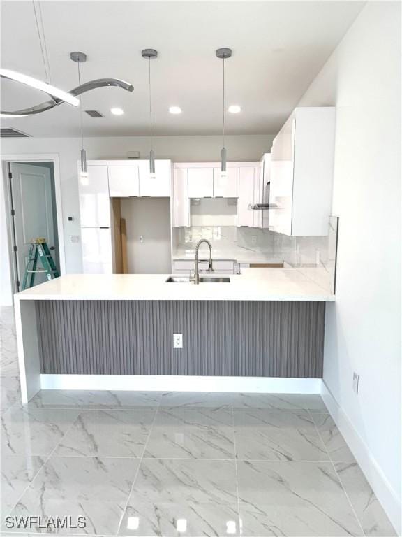 kitchen featuring decorative backsplash, marble finish floor, white cabinetry, and a sink