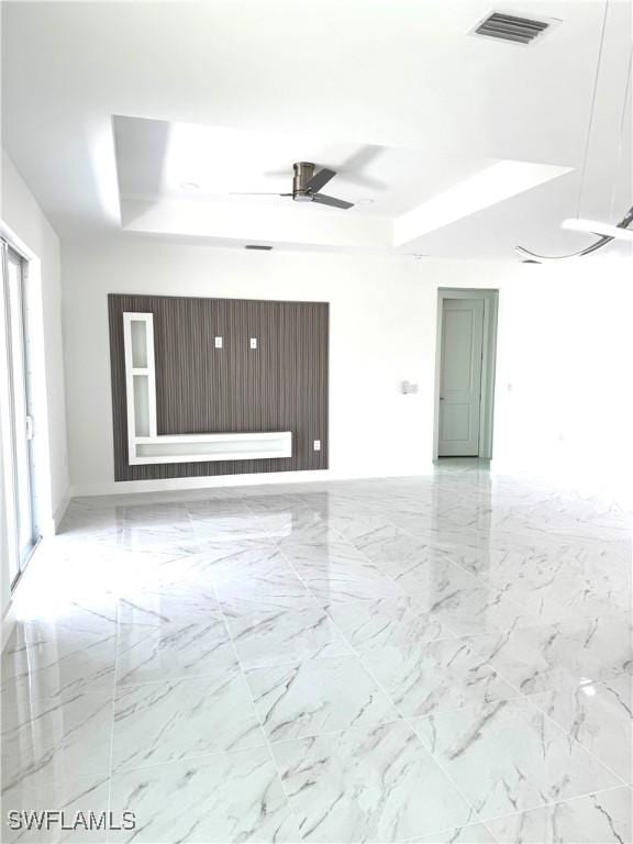 unfurnished room featuring a tray ceiling, marble finish floor, visible vents, and ceiling fan