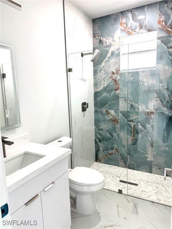 bathroom featuring a marble finish shower, marble finish floor, toilet, and vanity