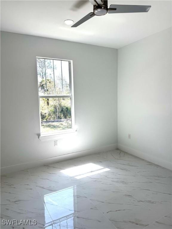 empty room featuring a ceiling fan, marble finish floor, and baseboards