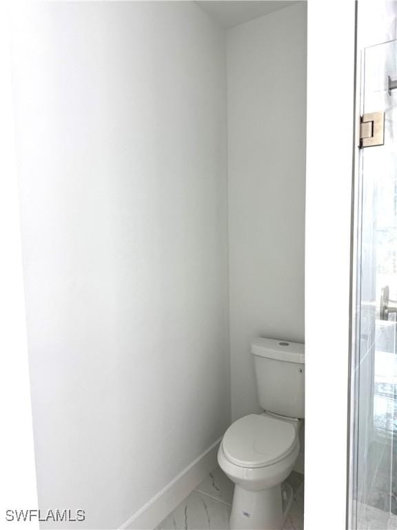 bathroom featuring baseboards, toilet, marble finish floor, and a stall shower