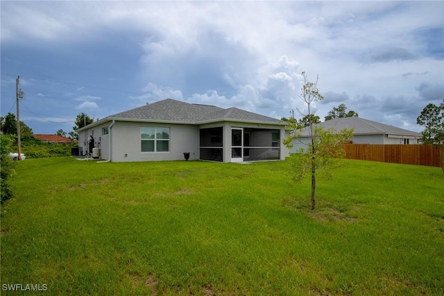 back of property with stucco siding, a lawn, a sunroom, and fence