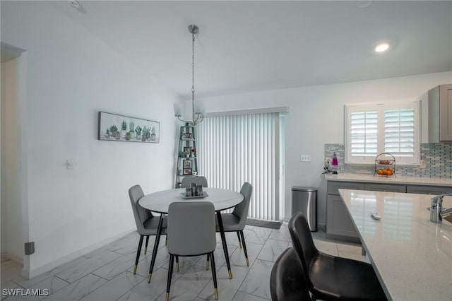 dining space with baseboards, lofted ceiling, and marble finish floor