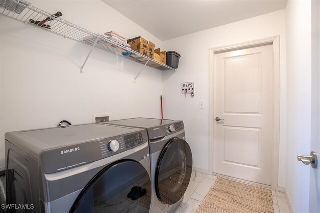 washroom with washing machine and clothes dryer, laundry area, marble finish floor, and baseboards