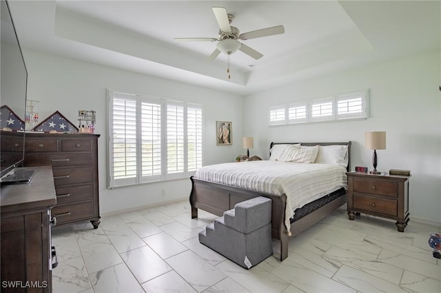 bedroom featuring baseboards, a raised ceiling, marble finish floor, and a ceiling fan