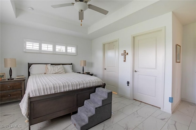 bedroom with baseboards, a raised ceiling, marble finish floor, and a ceiling fan