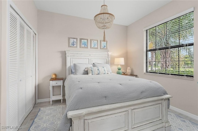 bedroom with a closet, a notable chandelier, and baseboards