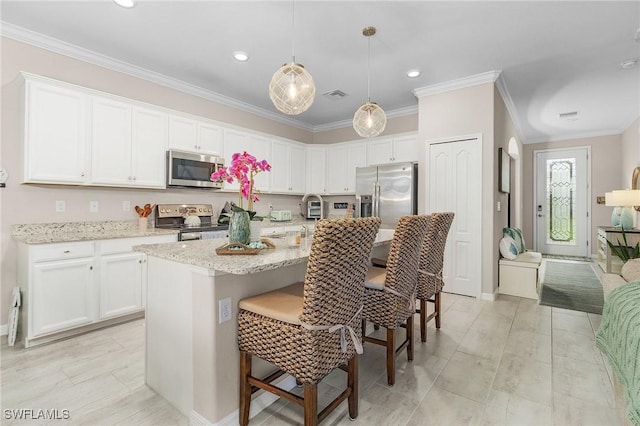 kitchen with white cabinets, a kitchen breakfast bar, stainless steel appliances, and crown molding