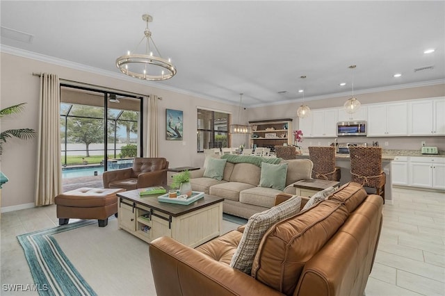 living area featuring visible vents, an inviting chandelier, and ornamental molding