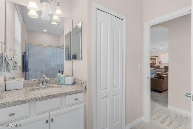 bathroom featuring vanity, a shower with shower curtain, baseboards, a closet, and a chandelier