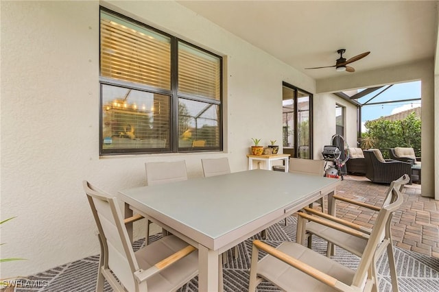 view of patio with outdoor dining area, a lanai, and a ceiling fan