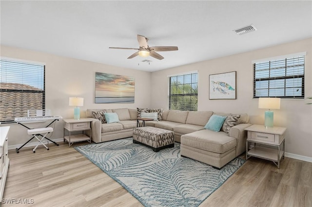 living area with visible vents, baseboards, ceiling fan, and light wood-style flooring