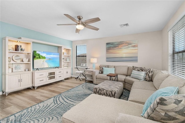 living room with visible vents, light wood-style flooring, and a ceiling fan