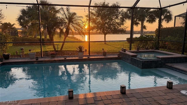 pool at dusk with glass enclosure and a pool with connected hot tub