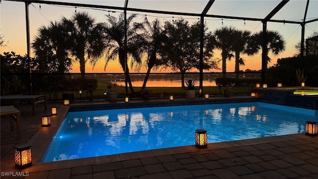 outdoor pool featuring a patio area, glass enclosure, and a water view