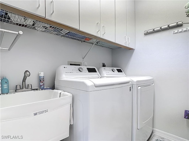 laundry room featuring a sink, baseboards, cabinet space, and washing machine and clothes dryer