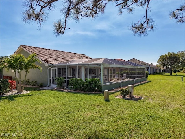 back of house featuring a yard, a tile roof, glass enclosure, and stucco siding