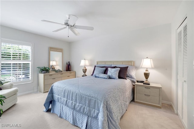 bedroom with ceiling fan, baseboards, a closet, and light carpet