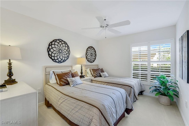 bedroom featuring baseboards, light colored carpet, and a ceiling fan