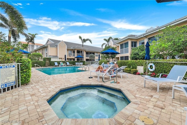 community pool featuring a community hot tub, a patio area, and fence