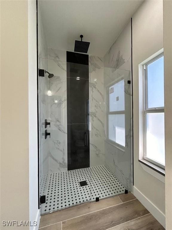 full bathroom featuring wood finish floors, a marble finish shower, and baseboards