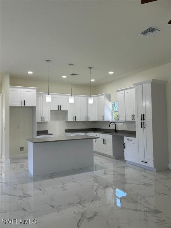 kitchen featuring visible vents, a center island, recessed lighting, white cabinets, and marble finish floor