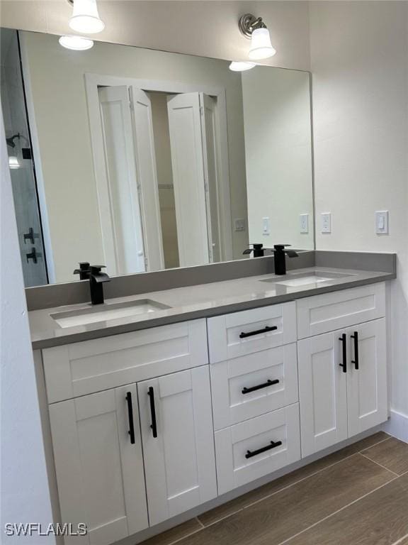 full bathroom featuring double vanity, wood tiled floor, and a sink