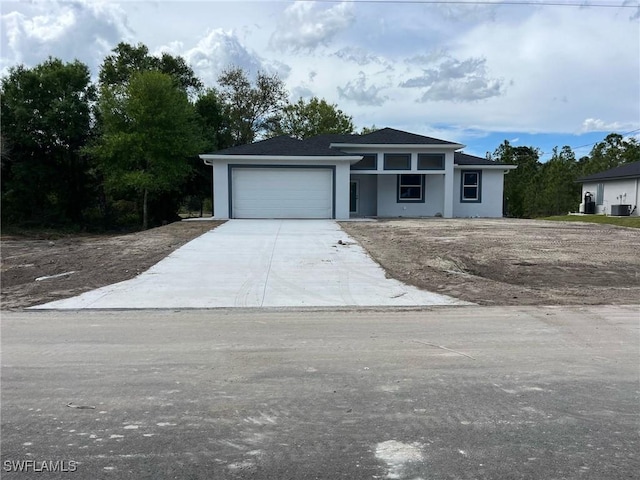 view of front facade with central air condition unit, stucco siding, driveway, and an attached garage