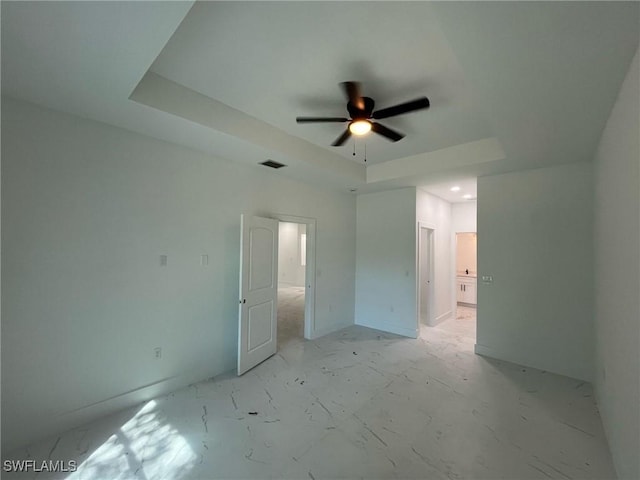 unfurnished bedroom featuring visible vents, a ceiling fan, and a tray ceiling