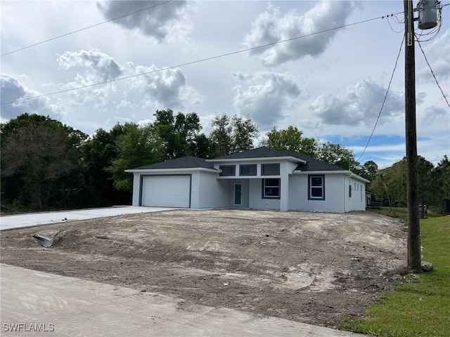 view of front facade with a garage, driveway, and stucco siding