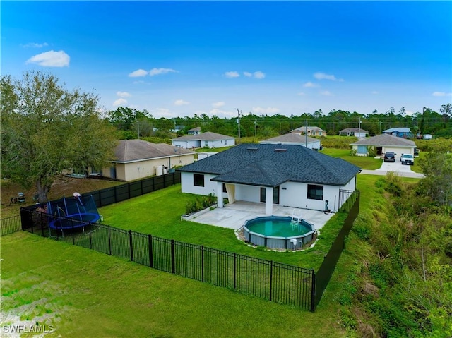 rear view of house with a fenced in pool, a trampoline, a lawn, a fenced backyard, and a patio area