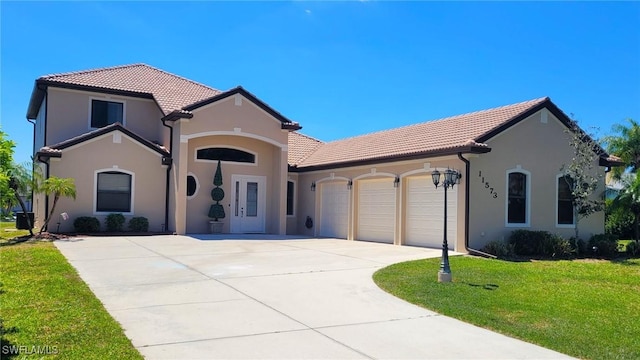 mediterranean / spanish house with a garage, stucco siding, a front lawn, and a tile roof