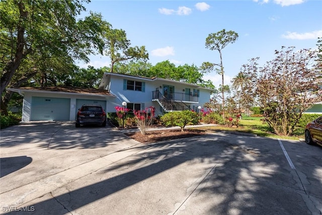 view of front of property with stairs, concrete driveway, a garage, and stucco siding