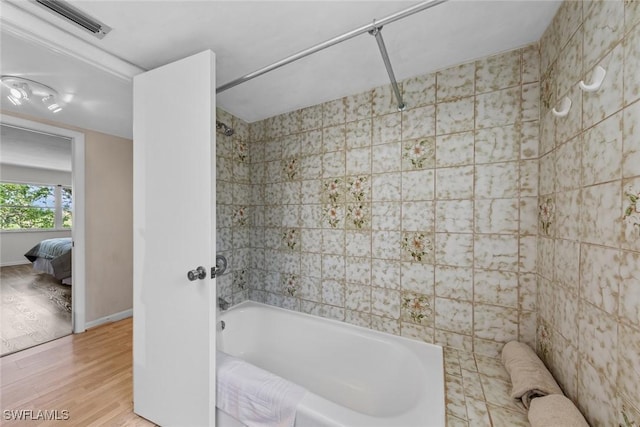 ensuite bathroom with wood finished floors, visible vents, baseboards,  shower combination, and ensuite bathroom