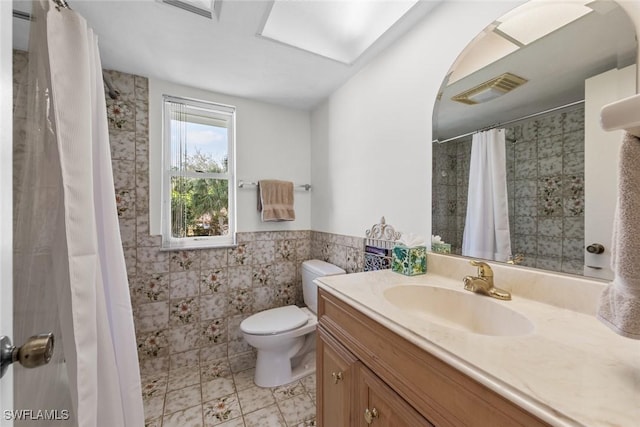 bathroom featuring vanity, visible vents, wainscoting, tile walls, and toilet