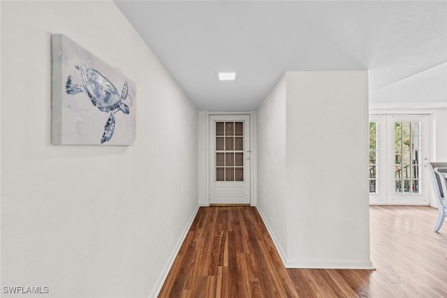 corridor featuring baseboards and wood finished floors