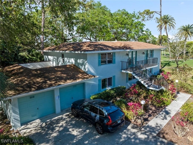 view of front facade with stucco siding, a garage, concrete driveway, and stairs