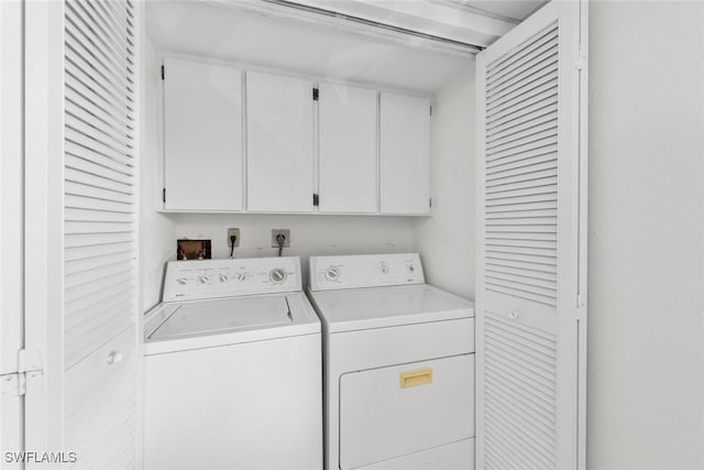 clothes washing area with cabinet space and washing machine and dryer